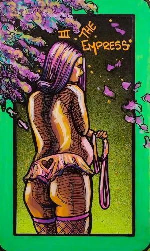 A tarot painting of The Empress. A long-haired figure stands turned slightly away, looking back over their shoulder. They wear fishnets and a short ruffled skirt with a heart stitched on the back. One hand holds a pink looped strap. Branches of blossoms scatter purple petals across a green background. The border is bright green, and the words “III The Empress” appear at the top in orange text. The image conveys sensual authority, abundance, and embodied power.