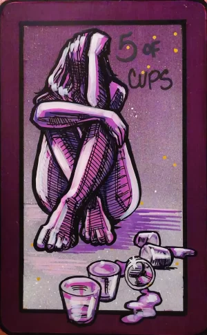 A painting of the 5 of Cups showing a seated figure with their head on their arms. Cups in front of them are overturned, with liquid spilled, while others remain standing.